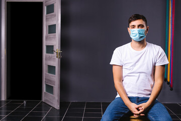 Fototapeta na wymiar Caucasian man sitting in an office wearing a medical mask waiting for the queue for a vaccine. Mass vaccination of employees on an office background.