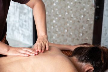 Asian woman having an aromatherapy with traditional Thai massage on back path in peaceful spa.