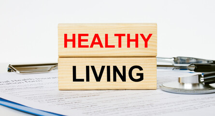 Wooden blocks with text Healthy Living on a clipboard and a stethoscope