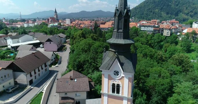 Drone flying over Saint Joseph church in small town Kranj, Slovenia. Aerial view of medieval town. Reveal of church tower bell. Tilt down