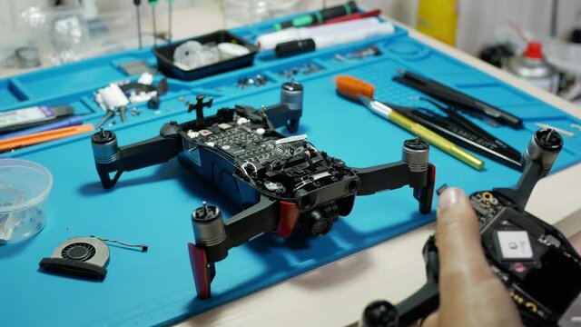 man disasembling the drone by special tools. removes the flex cable