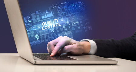 Businessman working on laptop with QUALITY CONTROL inscription, cyber technology concept