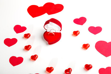 Red and purple hearts of different sizes for Valentine's day and glass hearts and a heart-shaped box with a ring on a white background.