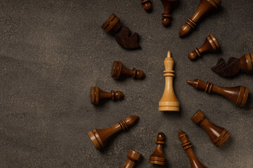 White king among black chess pieces on dark background