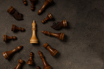 White king among black chess pieces on dark background