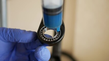 the mechanic rotates the bearing and lubricates it with a syringe