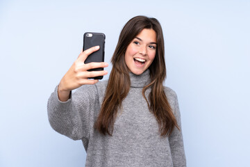 Teenager Brazilian girl over isolated blue background making a selfie