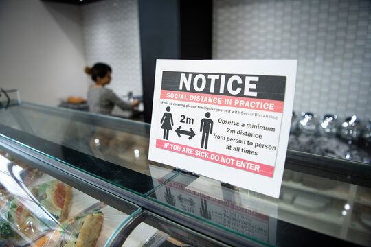 Close up social distancing reminder sign on display case in bakery