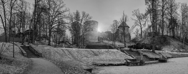 Panoramic black and white image of Cesis medieval castle ruins in a beautiful park with frozen lake and stone stairs in Cesis, Latvia
