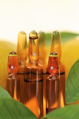 Vitamin C injection.A solution of vitamin C in brown glass ampoules , lemons with green leaves on a...