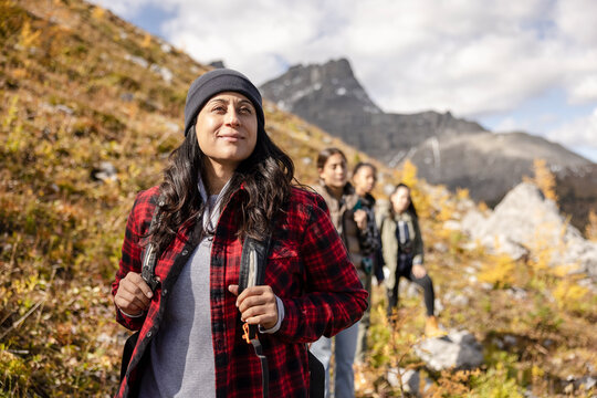 Serene woman hiking with daughter and friends on sunny autumn mountain
