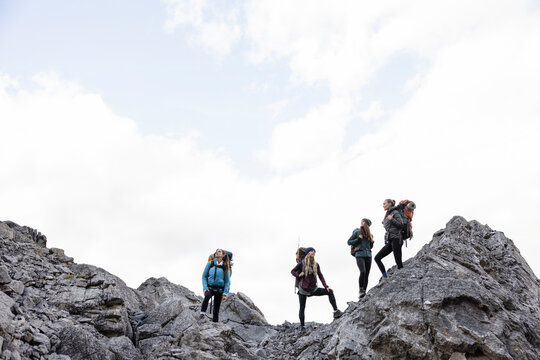 Young women friends hiking on top of craggy mountain
