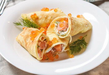 Delicious breakfast - crepes with smoked salmon, sour cream and caviarch on concrete background