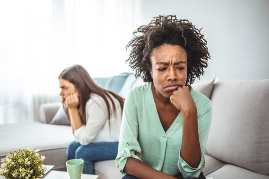 Two Female Friends Sitting On Sofa And Arguing With Each Other. Friendship, Quarrel, Female Disagreement, Copy Space. Angry Friends Or Roommates Sitting On A Sofa In The Living Room At Home