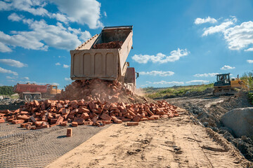 Fototapeta premium truck unloads old brick on a road under construction to a new construction site