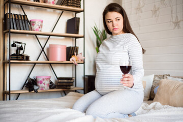 Pregnant woman keeping glass of wine. Future mother drinking alcohol while expecting little baby. Concept of unhealthy lifestyle and harmfulness.