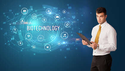 Businessman thinking in front of technology related icons and BIOTECHNOLOGY inscription, modern technology concept