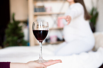 Pregnant woman keeping glass of wine. Future mother drinking alcohol while expecting little baby. Concept of unhealthy lifestyle and harmfulness.