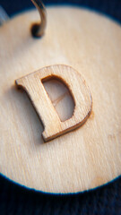 Letra d tallada en madera pegada con pegamento sobre chapa redonda de madera de llavero