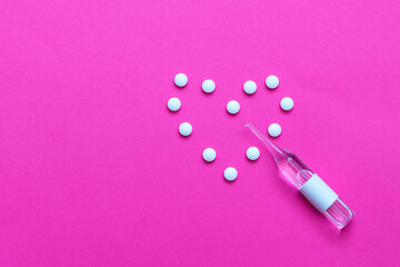 Heart made of white pills tablets with glass ampoule. Pink background. Photo horizontal with place for text.