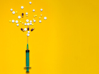 Vaccination against the Covid19 virus. Syringe. Yellow, white tablets, pills. Treatment. Yellow background with a free window for an inscription.