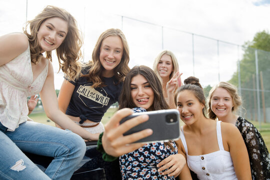 Happy teenage girl friends taking selfie with smart phone