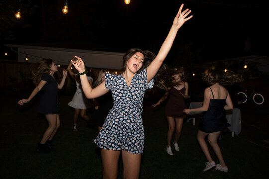 Carefree Teenage Girl Dancing With Friends At Backyard Night Party