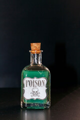 Concept of toxic thing. Transparent bottle with purple liquid simulating poison. The label reads poison along with a skull and two tibias