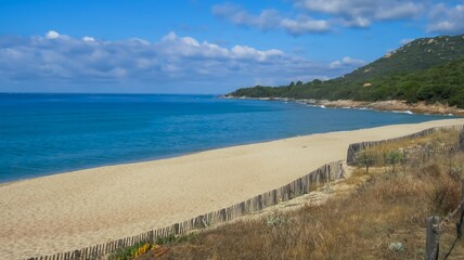 beautiful white sand beach, blue turquoise water bay and forested coastline