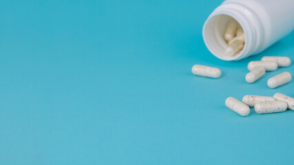 white medical pills spilling out of bottle on a blue background