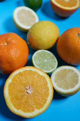 Whole and split oranges, limes and lemons with skin on a blue background. CITRUS CITRIC