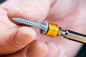 magnetic nozzle for a screwdriver, holds a self-tapping screw, black background