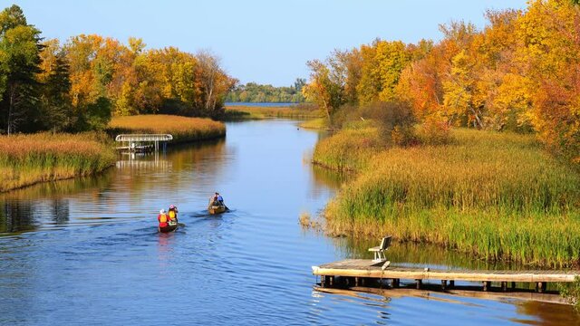 Mississippi River and two canoes head north toward Bemidji Minnesota near highway 2. Beautiful autumn colors in the trees along the river, a few miles from the source at Lake Itasca
