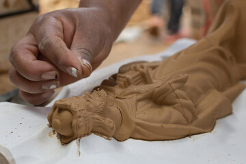 Hand of an artisan woman retouching a clay figure
