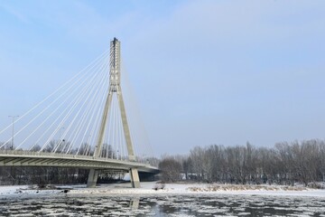 Swietokrzyski Bridge over Vistula river, Warsaw, Poland. Modern, cable-stayed bridge with single tower and cables attached supporting the deck. Winter time, fragments of ice float on the river
