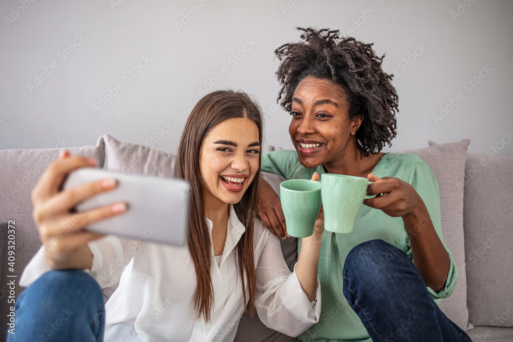 Wall mural shot of a two female friends taking selfie in the apartment. my roomies. shot of two young women tak