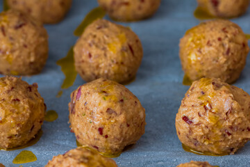 Falafel roh in Reihe auf einem Backpapier mit Öl