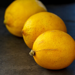 Drei Zitronen hintereinander aufgelegt versetzt auf dunklem Hintergrund