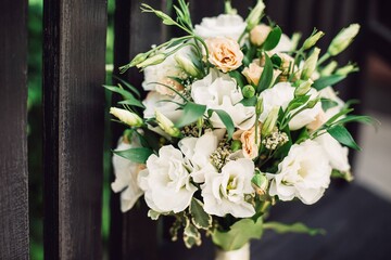 The bride's bouquet is placed vertically on a black bench. Close-up. Pastel colors.
