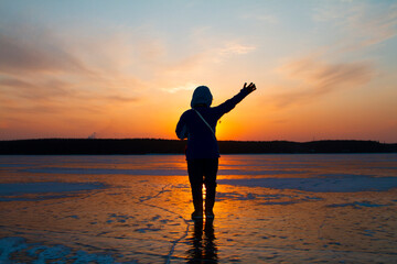 Fototapeta premium Silhouette of a person on the frozen lake in sunset.