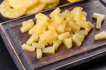 Pineapple canned with pieces on a wooden cutting board