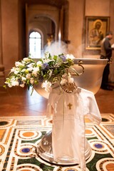 Baptismal font decorated with flowers. Christening shirt for Christening
