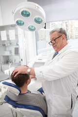 Obraz premium Vertical shot of a senior doctor examining lymphatic nods of a patient before dental treatment