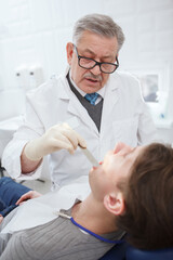 Obraz premium Vertical shot of a professional dentist talking to the patient while examining his teeth
