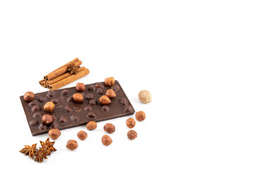 Chocolate bar with whole hazelnuts, cinnamon sticks and anise stars on a white background