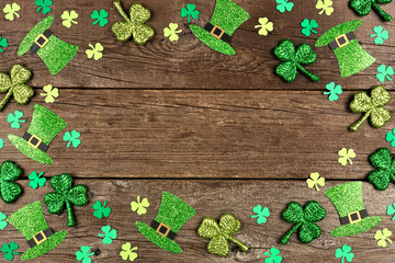 St Patricks Day shamrock and leprechaun hat frame. Overhead view over a rustic wood background with...