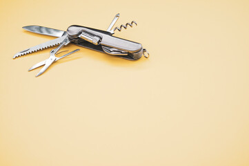 High angle shot of a swiss army knife on a yellow surface