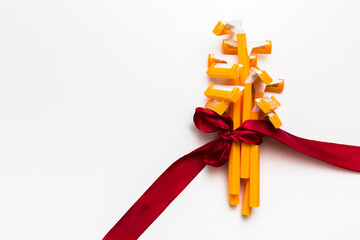 Bunch of yellow disposable shaving razors tied with red ribbon in bow as gift at white background, skin care and hair removal backdrop