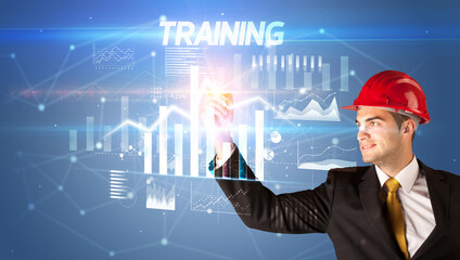 Handsome businessman with helmet drawing TRAINING inscription, architecture business plan concept