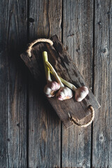 Fresh garlic heads in wooden bord on old dark wooden background